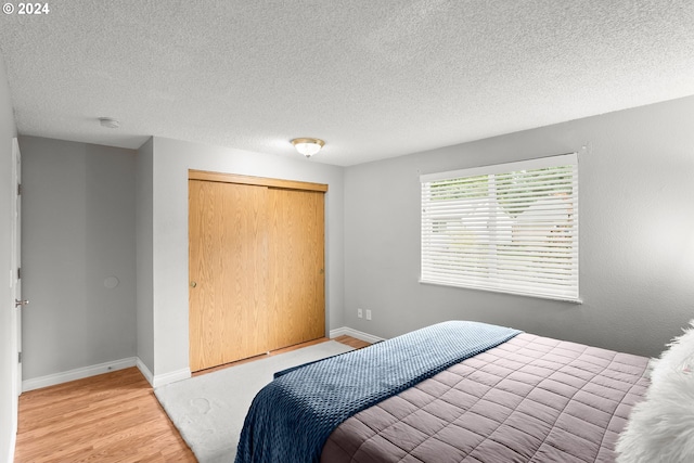 bedroom with hardwood / wood-style floors, a textured ceiling, and a closet