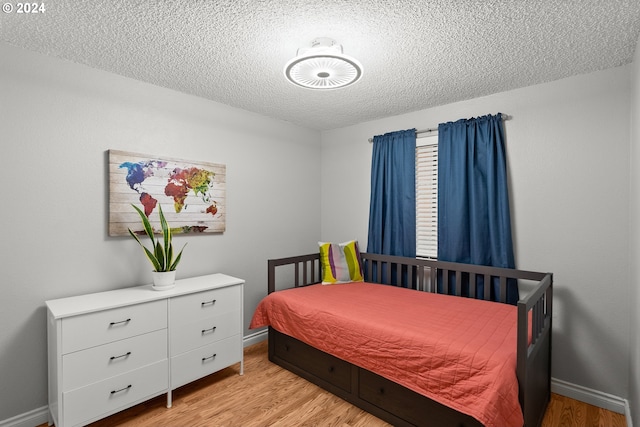 bedroom with a textured ceiling and light hardwood / wood-style flooring