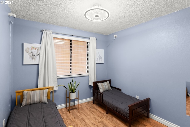 bedroom with a textured ceiling and light hardwood / wood-style floors