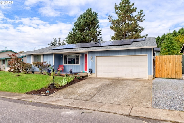 ranch-style home featuring a front lawn, a garage, and solar panels