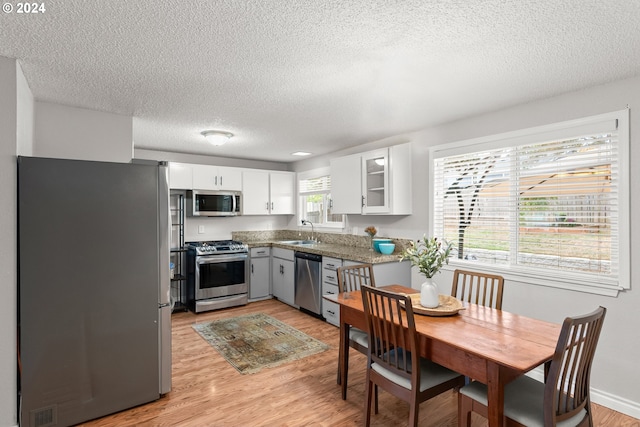 kitchen with light wood-type flooring, stainless steel appliances, white cabinetry, and sink