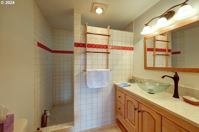 bathroom featuring vanity, tile walls, tile patterned floors, tiled shower, and toilet