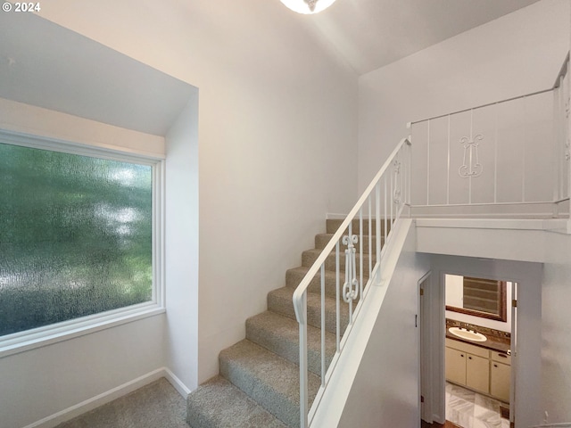 staircase featuring lofted ceiling, sink, and carpet