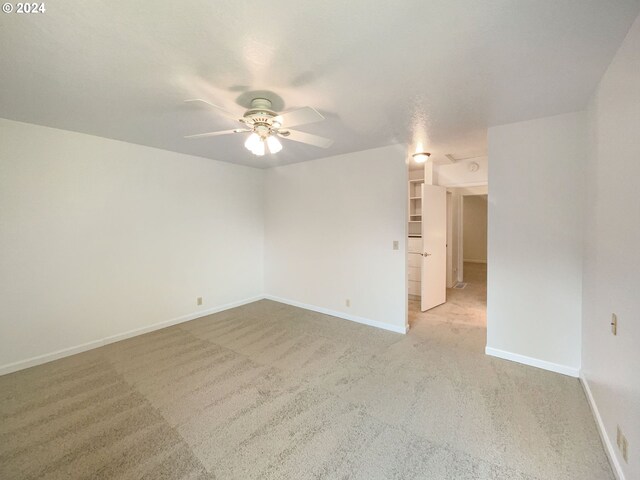 carpeted spare room featuring ceiling fan