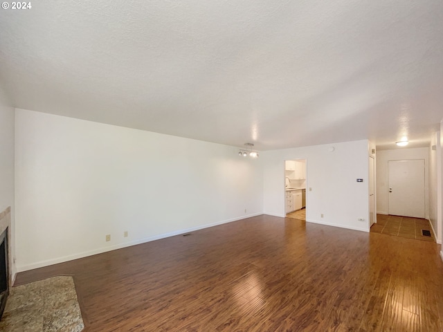 unfurnished living room with a textured ceiling and dark hardwood / wood-style floors