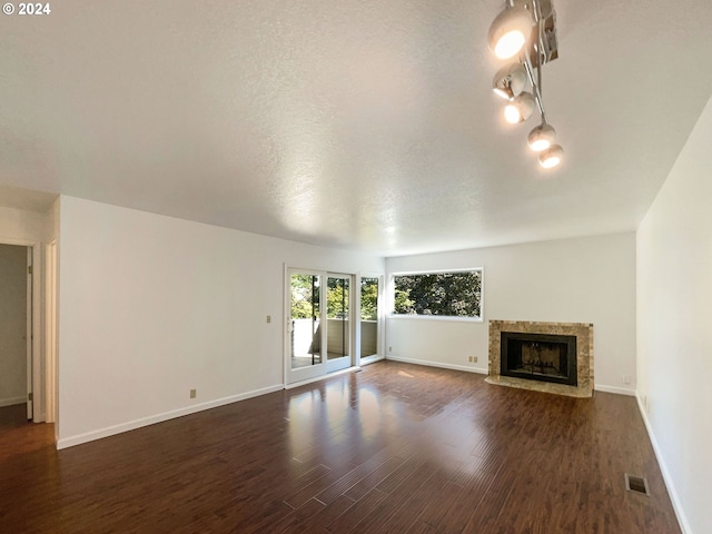 unfurnished living room featuring a fireplace, dark wood-type flooring, and a textured ceiling