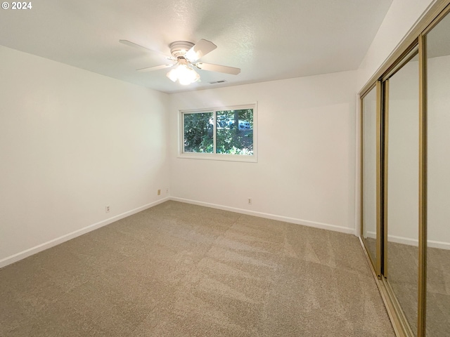 unfurnished bedroom with light colored carpet, ceiling fan, and a closet