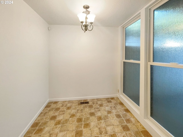 unfurnished room featuring a chandelier