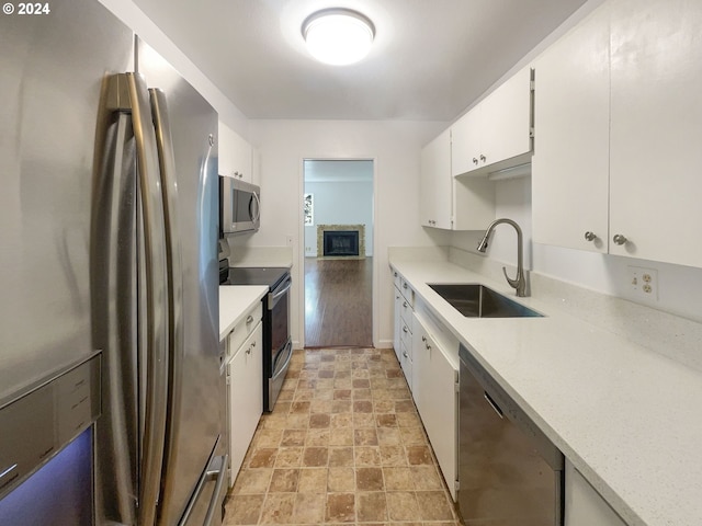 kitchen with stainless steel appliances, white cabinetry, and sink