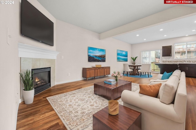 living room featuring beamed ceiling, a fireplace, and hardwood / wood-style flooring