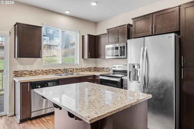 kitchen with dark brown cabinets, stainless steel appliances, a kitchen island, and sink