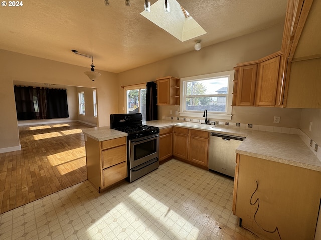 kitchen featuring sink, a textured ceiling, kitchen peninsula, pendant lighting, and light hardwood / wood-style flooring