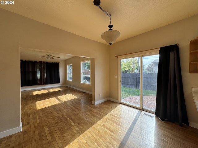 kitchen with kitchen peninsula, a textured ceiling, light hardwood / wood-style flooring, a skylight, and pendant lighting