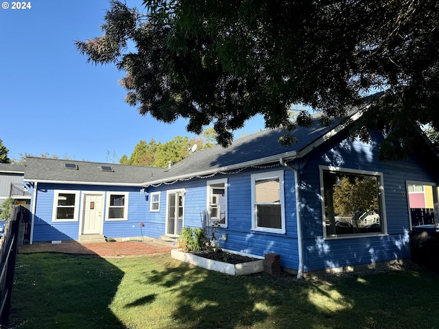 back of house featuring a yard, a garage, and an outdoor structure