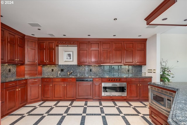 kitchen featuring dark stone countertops, stainless steel appliances, sink, and decorative backsplash