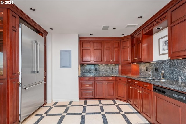 kitchen featuring sink, high end fridge, backsplash, dark stone countertops, and paneled dishwasher