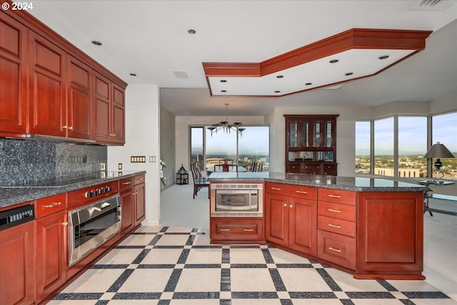 kitchen featuring dark stone counters, backsplash, oven, and pendant lighting