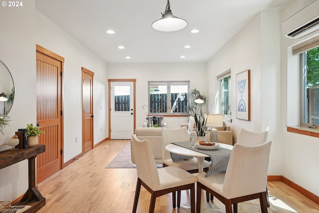 dining room with plenty of natural light, a wall mounted AC, and light wood-type flooring