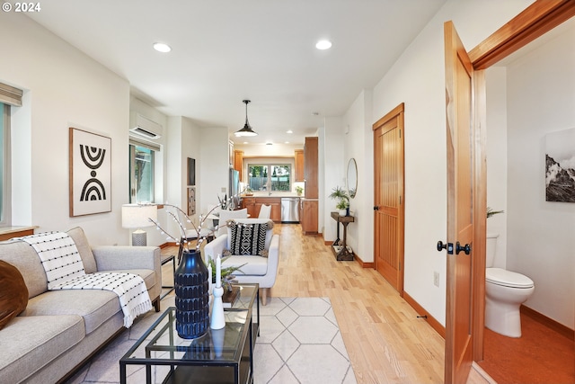 living room featuring a wall mounted air conditioner and light wood-type flooring