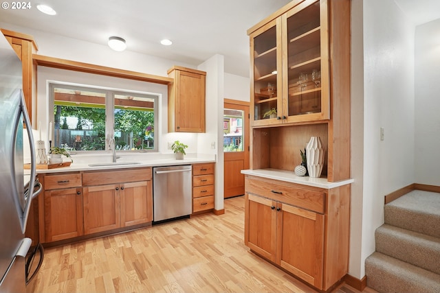 kitchen with appliances with stainless steel finishes, sink, and light hardwood / wood-style flooring