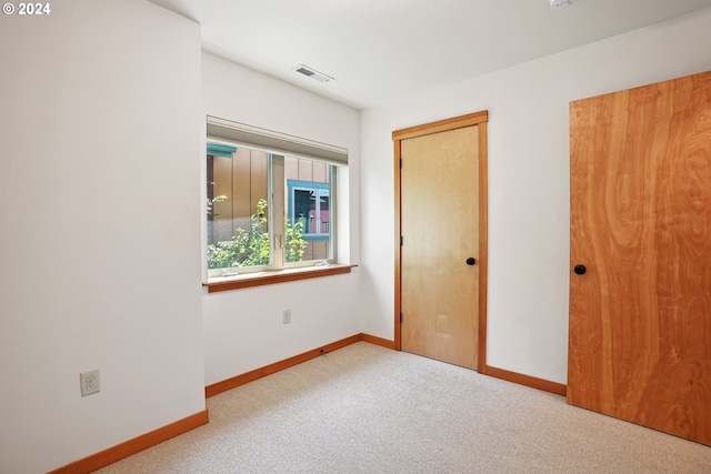 unfurnished bedroom with a closet and light colored carpet