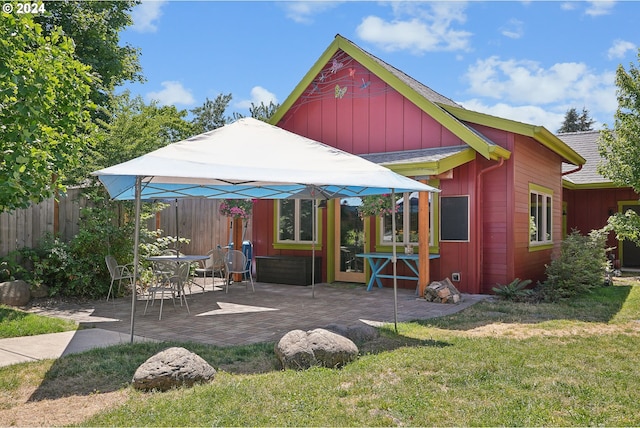 back of house with a patio and a lawn