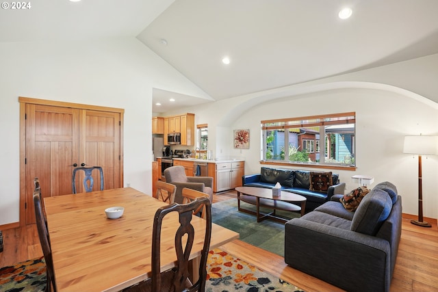 dining space with light wood-type flooring, high vaulted ceiling, and a wealth of natural light