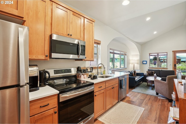 kitchen with lofted ceiling, sink, stainless steel appliances, and light hardwood / wood-style flooring