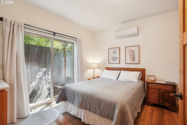 bedroom with a wall unit AC, dark wood-type flooring, and access to outside