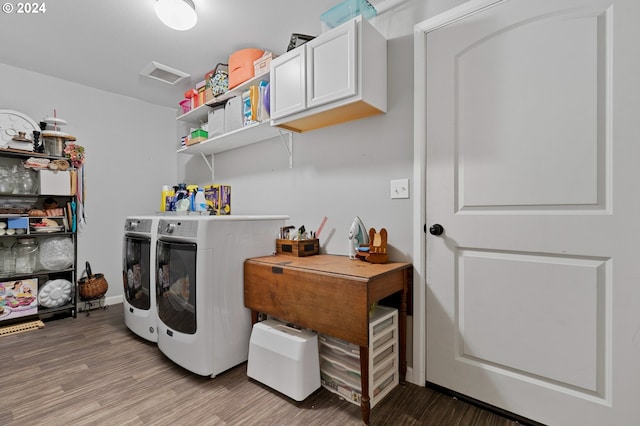 clothes washing area with cabinets, washer and dryer, and light hardwood / wood-style floors