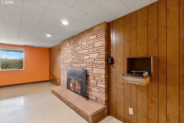 living room featuring wooden walls, a fireplace, and a paneled ceiling