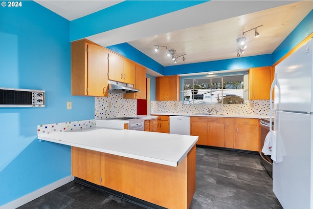 kitchen with sink, kitchen peninsula, white appliances, backsplash, and rail lighting