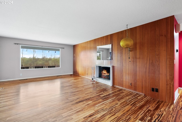 unfurnished living room with wood-type flooring and wood walls