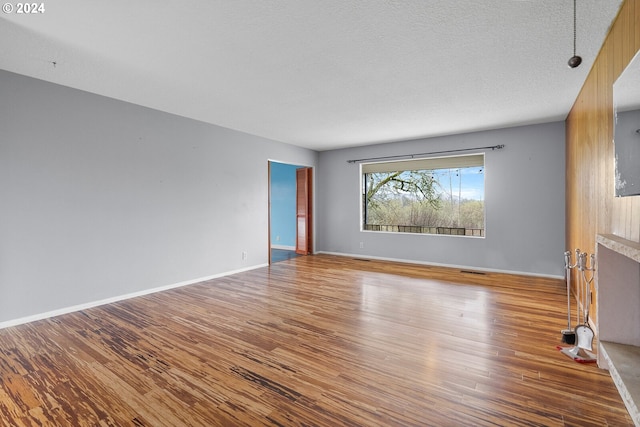 unfurnished living room featuring a textured ceiling, a fireplace, and hardwood / wood-style floors