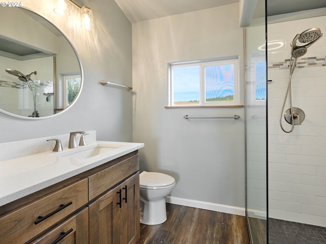 bathroom featuring a tile shower, vanity, toilet, and hardwood / wood-style flooring