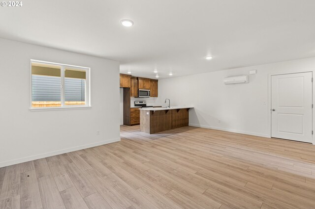 interior space with a wall unit AC, sink, and light wood-type flooring