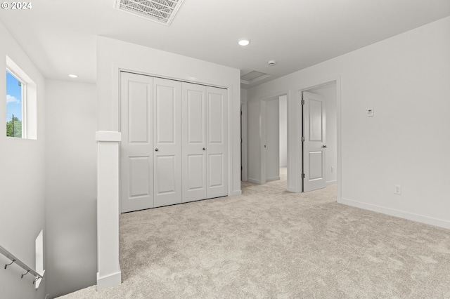 unfurnished bedroom with light carpet and a closet