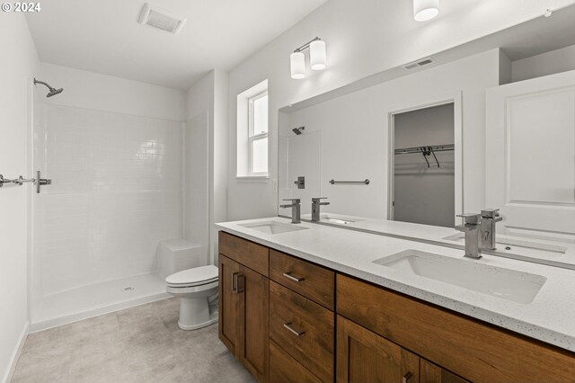 bathroom featuring dual vanity, tile floors, toilet, and a shower