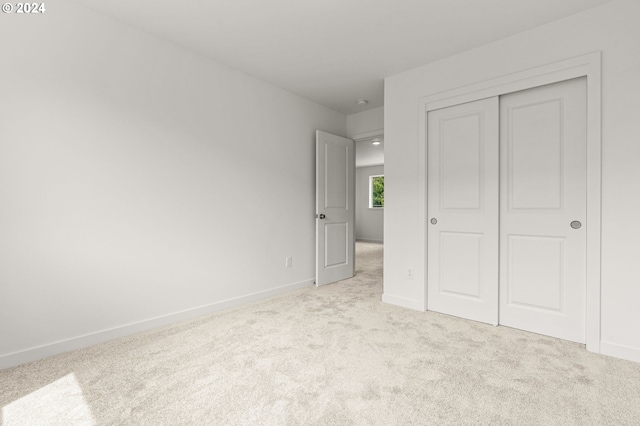 unfurnished bedroom with a closet and light colored carpet