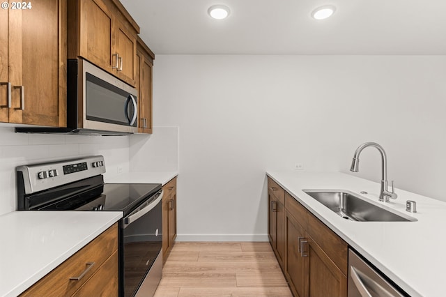 kitchen with sink, light hardwood / wood-style flooring, backsplash, and appliances with stainless steel finishes