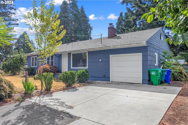 single story home featuring an attached garage, driveway, a chimney, and roof with shingles