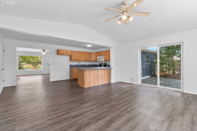 kitchen featuring ceiling fan, kitchen peninsula, vaulted ceiling, and wood-type flooring