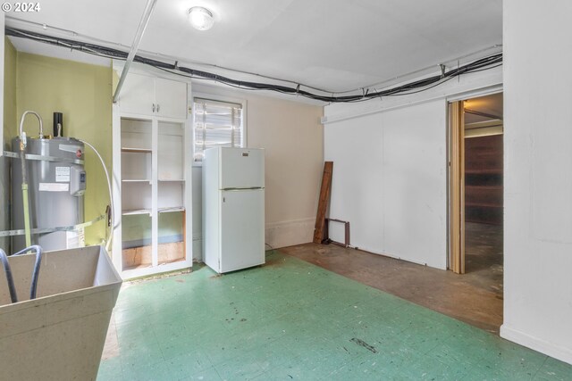 basement featuring white refrigerator and strapped water heater