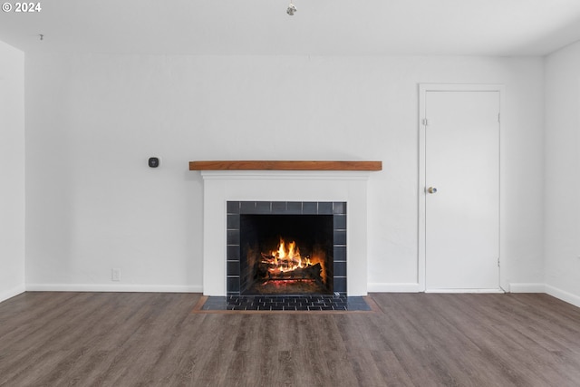 room details with hardwood / wood-style floors and a tiled fireplace