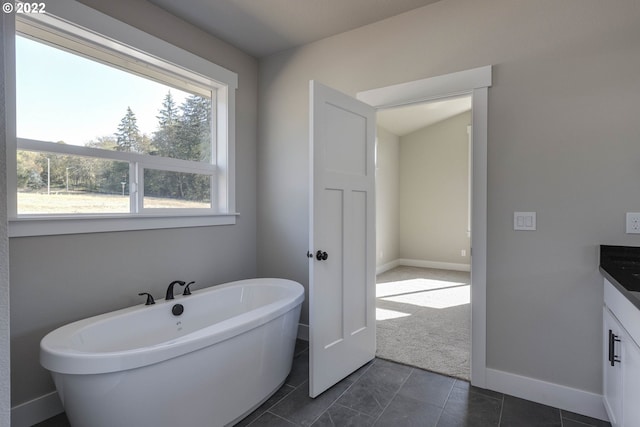 bathroom featuring vanity, a bath to relax in, and tile flooring