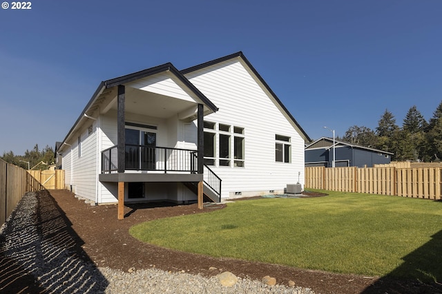 rear view of house featuring central AC unit and a lawn