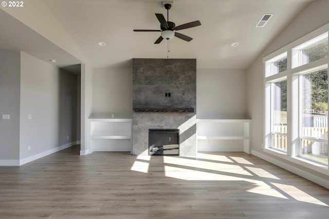 unfurnished living room featuring ceiling fan, light hardwood / wood-style floors, a fireplace, and vaulted ceiling