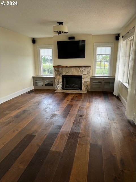 unfurnished living room featuring dark hardwood / wood-style flooring, a high end fireplace, and a textured ceiling