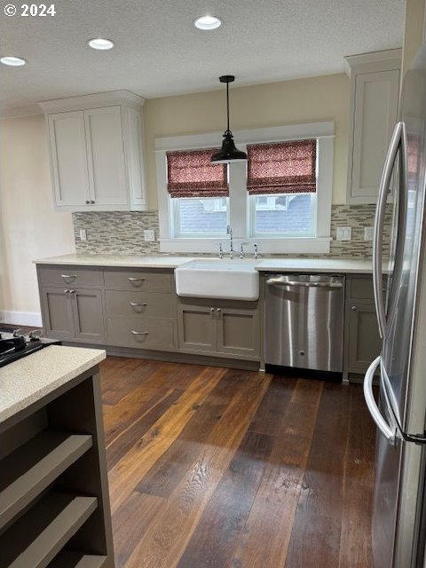 kitchen featuring dark wood-type flooring, stainless steel appliances, gray cabinets, sink, and tasteful backsplash