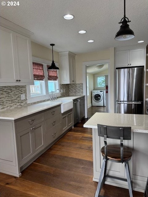 kitchen with appliances with stainless steel finishes, backsplash, dark hardwood / wood-style floors, and a wealth of natural light